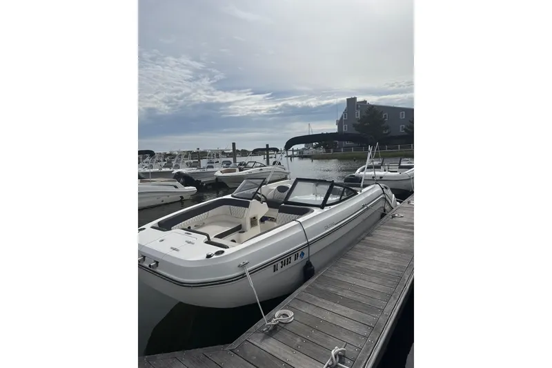 The Image of 2023 Bayliner DX 2200 boat docked at a marina under a cloudy sky. - 0