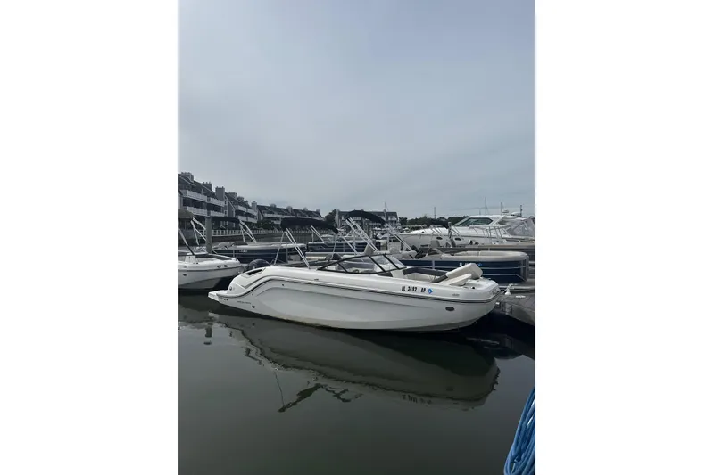 Slide: The Image of 2023 Bayliner DX 2200 boat docked in a marina, surrounded by other vessels. - 1
