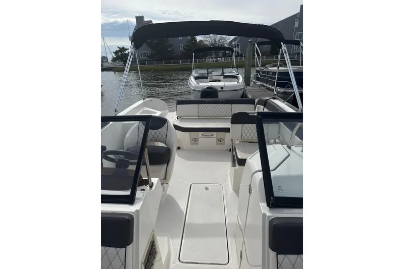 Slide: The Image of 2023 Bayliner DX 2200 boat interior with seating and canopy, docked by the water. - 3