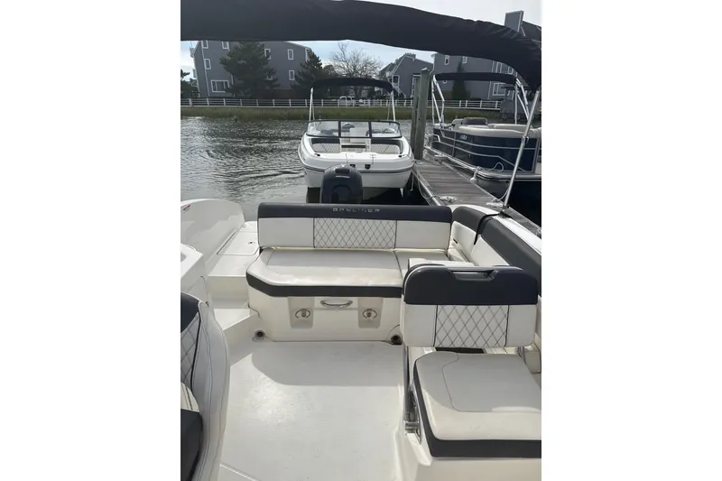 Slide: The Image of 2023 Bayliner DX 2200 boat interior with cushioned seating at a marina. - 4