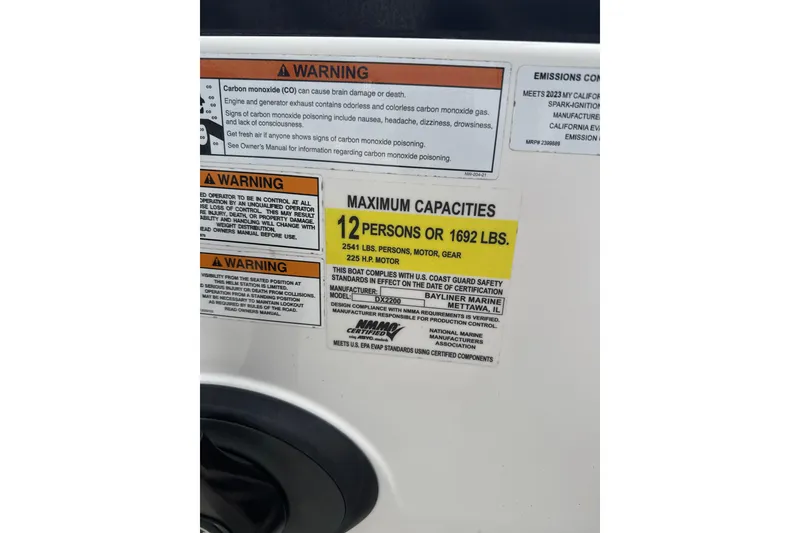 Slide: The Image of Warning labels and capacity information on a 2023 Bayliner DX 2200 boat. - 7