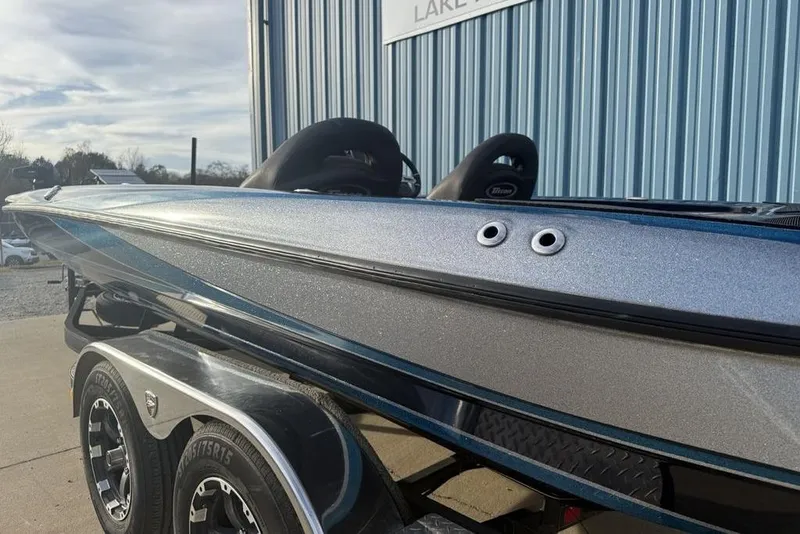 Slide: The Image of 2021 Triton 21 TrX boat on trailer, metallic finish, parked near blue building. - 3