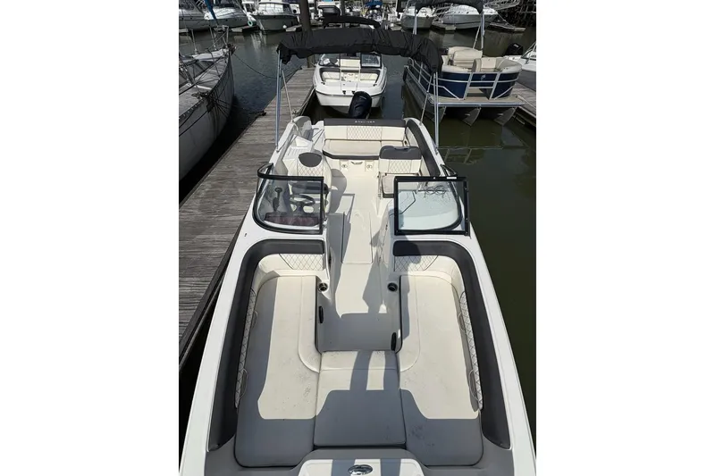 Slide: The Image of 2023 Bayliner DX 2200 boat docked at marina, featuring spacious seating and sleek design. - 2