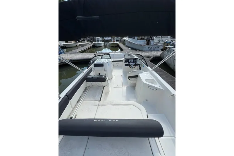 Slide: The Image of 2023 Bayliner DX 2200 boat interior at marina, featuring seating and steering console. - 3