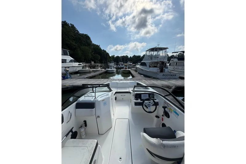 Slide: The Image of 2023 Bayliner DX 2200 boat docked at a marina under a partly cloudy sky. - 4