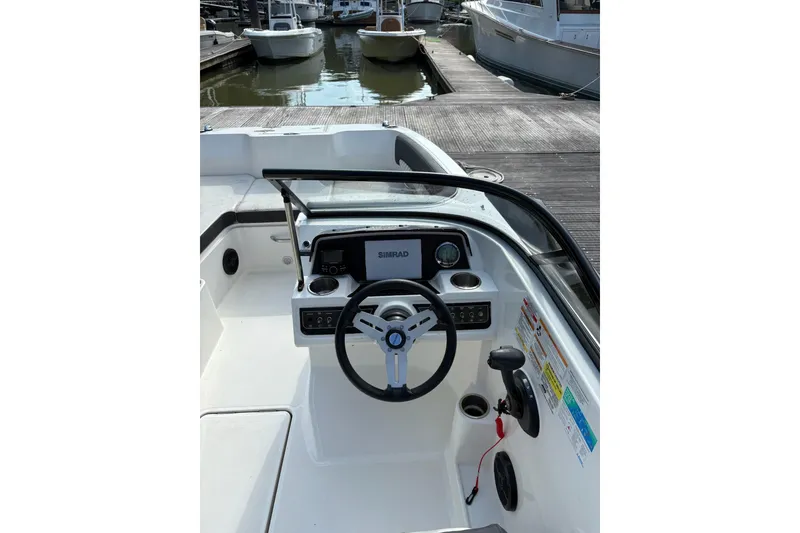 Slide: The Image of 2023 Bayliner DX 2200 boat dashboard with steering wheel and controls at marina. - 5