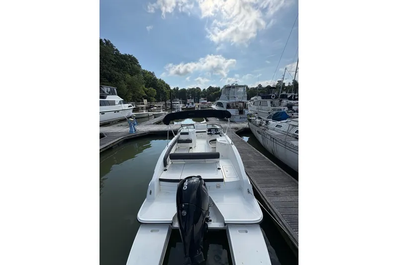 Slide: The Image of 2023 Bayliner DX 2200 boat docked at a marina under a partly cloudy sky. - 6