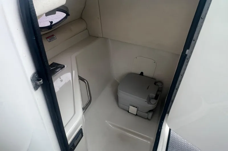 Slide: The Image of 2005 Sea Ray 270 Sundeck interior with portable toilet in compact cabin space. - 21