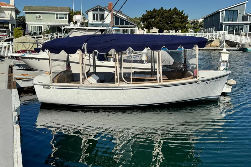 The Image of 2008 Duffy Snug Harbor boat docked with blue canopy and waterfront homes in background. - 0
