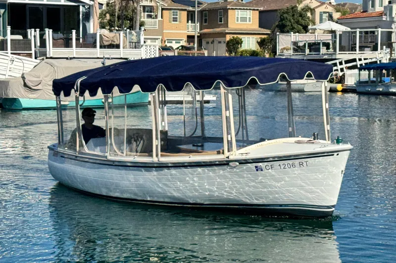 Slide: The Image of 2008 Duffy Snug Harbor boat with blue canopy cruising in a residential marina. - 2