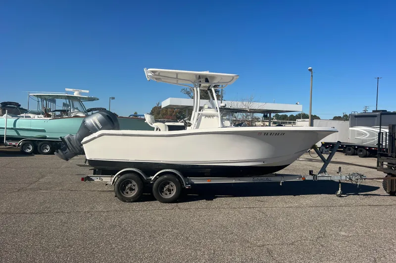 Slide: The Image of 2013 Tidewater 216 CC Adventure boat on trailer in parking lot under clear blue sky. - 2