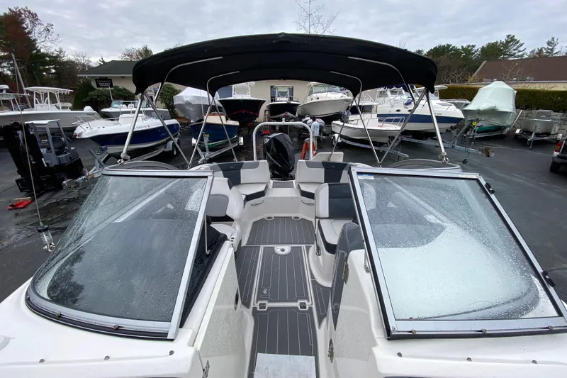 Slide: The Image of 2021 Chaparral 230 Suncoast boat with black canopy in a marina setting. - 17