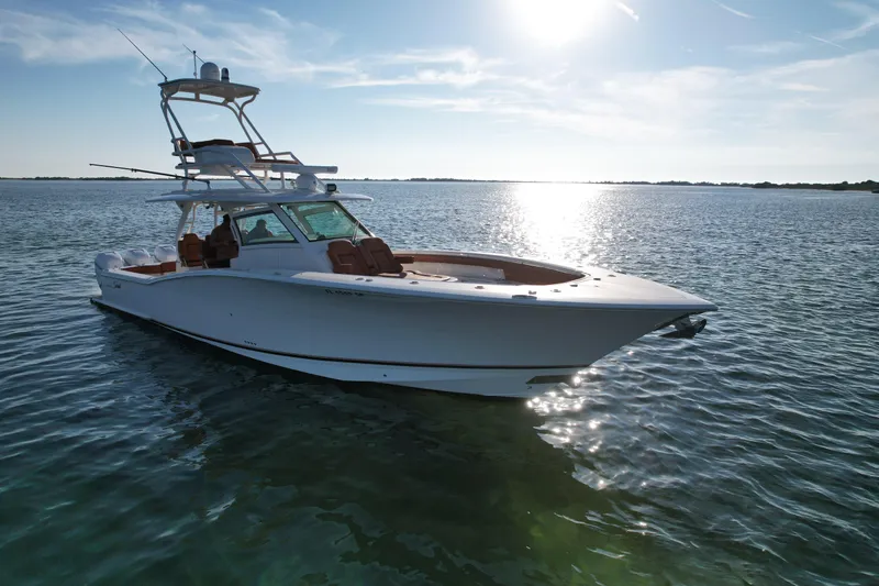 Slide: The Image of 2019 Scout 420 LXF boat on calm water under a bright sun. - 15