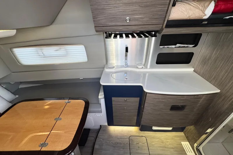 Slide: The Image of Interior of 2019 Scout 420 LXF boat featuring a compact kitchenette and dining area. - 46