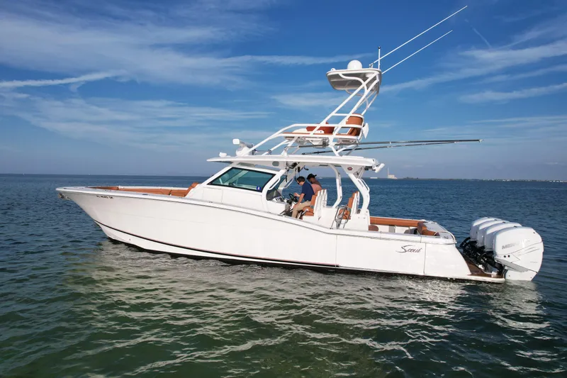 Slide: The Image of 2019 Scout 420 LXF boat cruising on open water under a clear blue sky. - 5