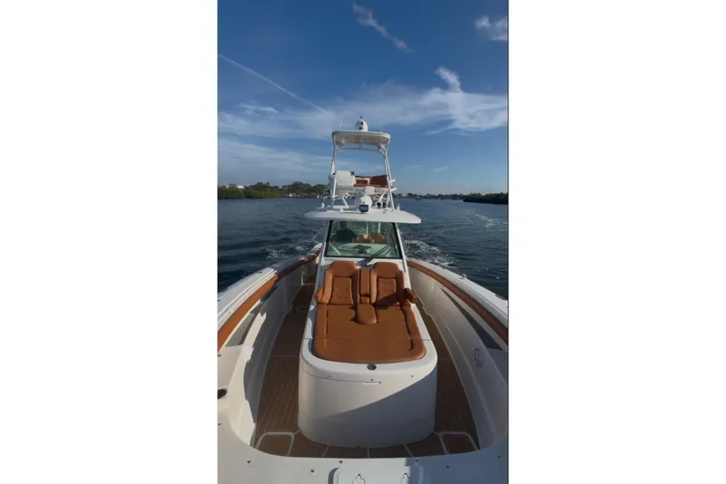 Slide: The Image of 2019 Scout 420 LXF boat cruising on a calm waterway under a clear blue sky. - 50