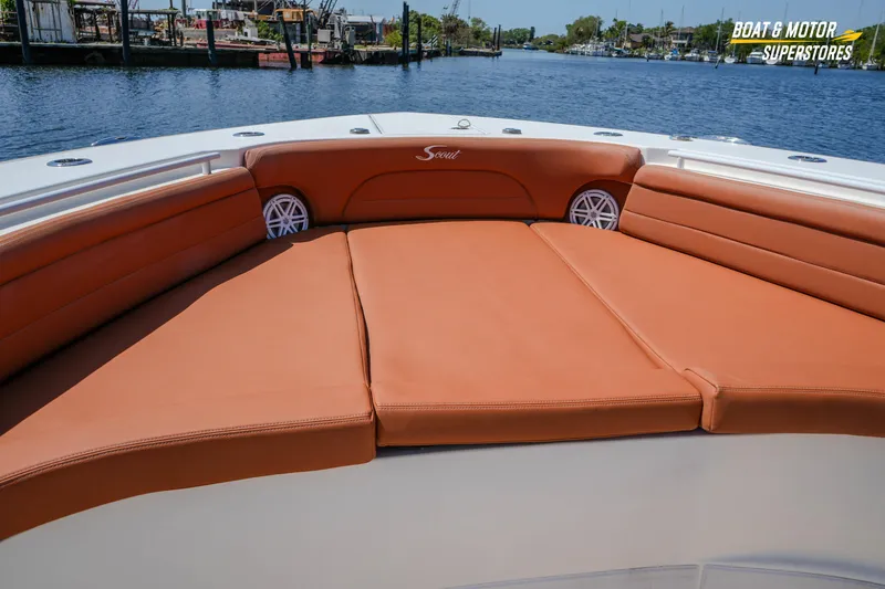 Slide: The Image of 2019 Scout 420 LXF boat with tan leather seating, docked by a serene waterfront. - 60