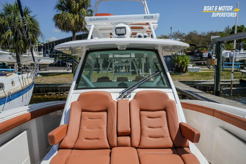 Slide: The Image of 2019 Scout 420 LXF boat with tan seating, docked at a marina under clear skies. - 63