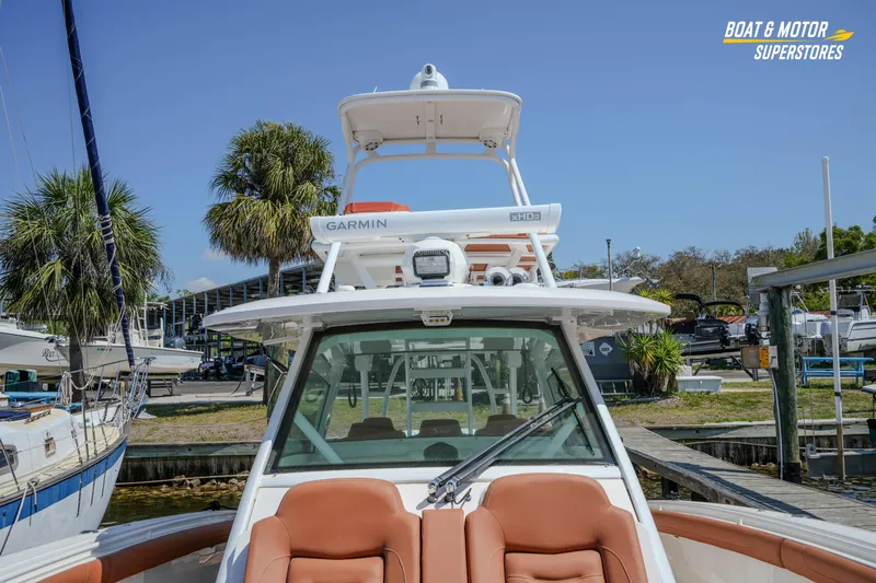 Slide: The Image of 2019 Scout 420 LXF boat docked, featuring Garmin equipment and luxurious seating. - 64