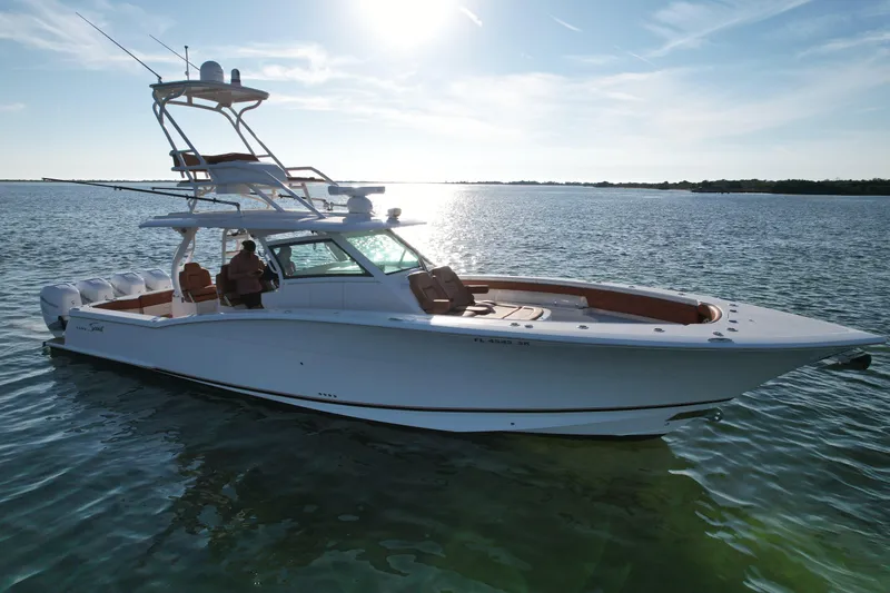Slide: The Image of 2019 Scout 420 LXF boat on calm water under a bright sunlit sky. - 7