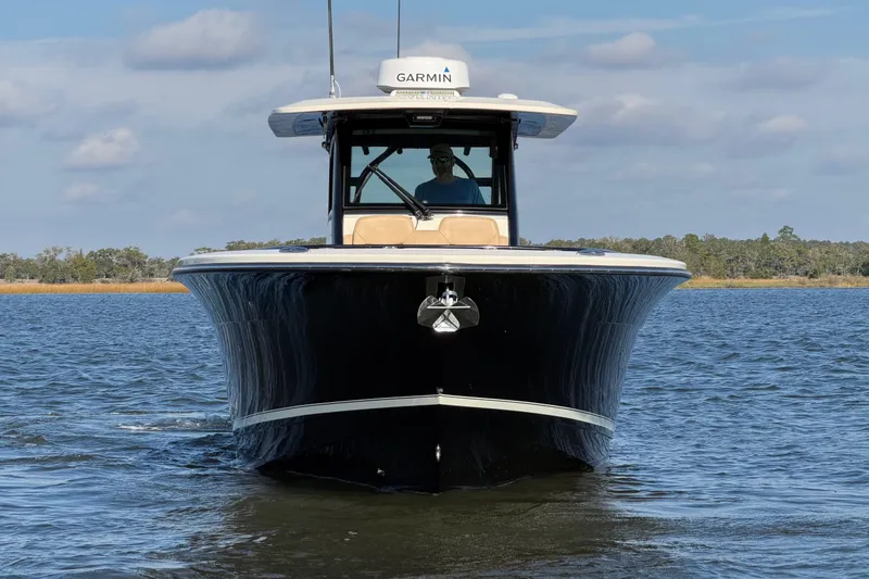 Slide: The Image of 2022 Scout 330 LXF boat on water, front view with clear sky background. - 12