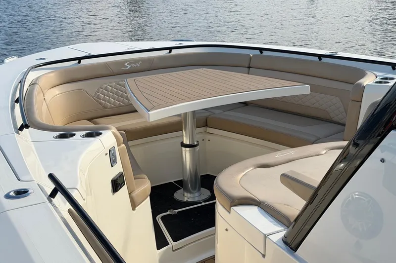 Slide: The Image of 2022 Scout 330 LXF boat interior with elegant seating and table, docked on water. - 30