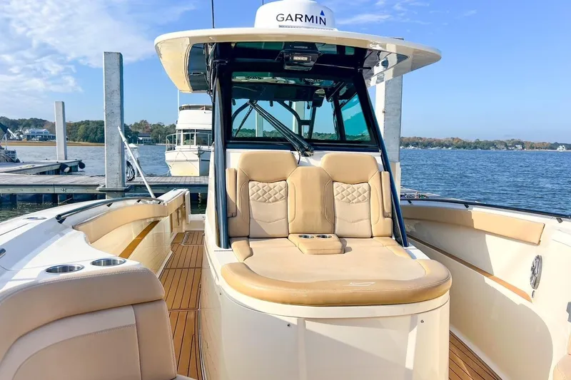 Slide: The Image of 2022 Scout 330 LXF boat interior with tan seating, docked by the water. - 35
