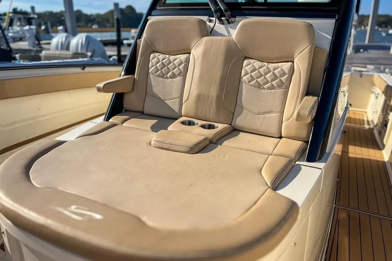 Slide: The Image of Luxurious seating on 2022 Scout 330 LXF boat, featuring beige upholstery and cup holders. - 36