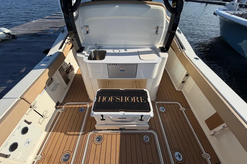 Slide: The Image of 2022 Scout 330 LXF boat interior with teak flooring and sink, docked by the water. - 43