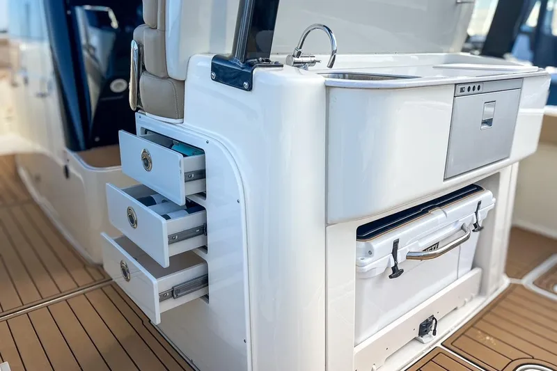 Slide: The Image of 2022 Scout 330 LXF boat interior with sink, drawers, and cooler on teak flooring. - 45