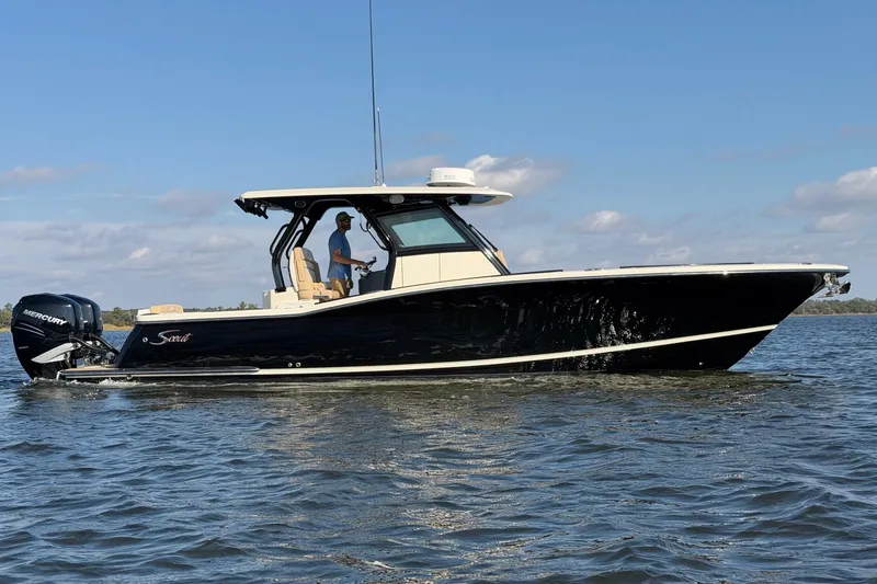 Slide: The Image of 2022 Scout 330 LXF boat cruising on calm water under a clear blue sky. - 5