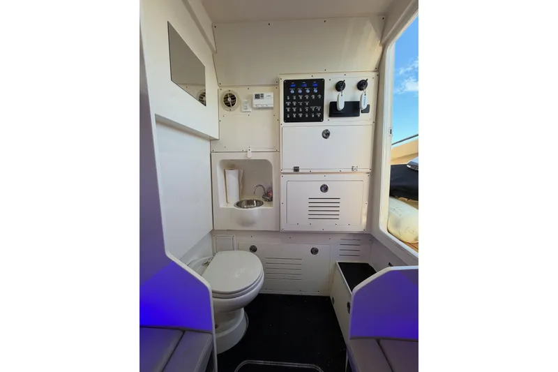 Slide: The Image of Interior of 2022 Scout 330 LXF boat featuring a compact bathroom with toilet and sink. - 57