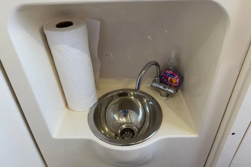 Slide: The Image of Compact sink area with paper towel and soap on a 2022 Scout 330 LXF boat. - 60