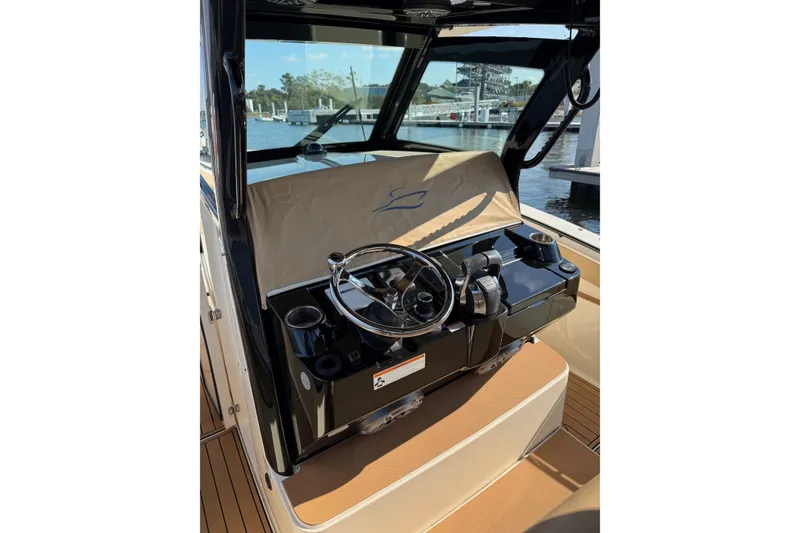 Slide: The Image of 2022 Scout 330 LXF boat helm with steering wheel and controls, dockside view. - 69