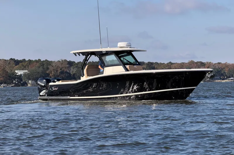 Slide: The Image of 2022 Scout 330 LXF boat cruising on a calm lake under a clear sky. - 7