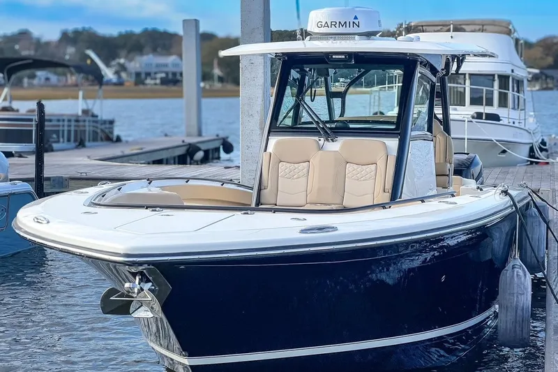 Slide: The Image of 2022 Scout 330 LXF boat docked, featuring Garmin equipment and luxurious seating. - 73