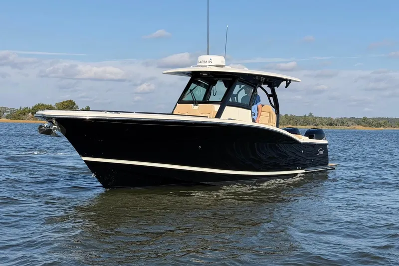 Slide: The Image of 2022 Scout 330 LXF boat on calm water under a clear sky. - 8
