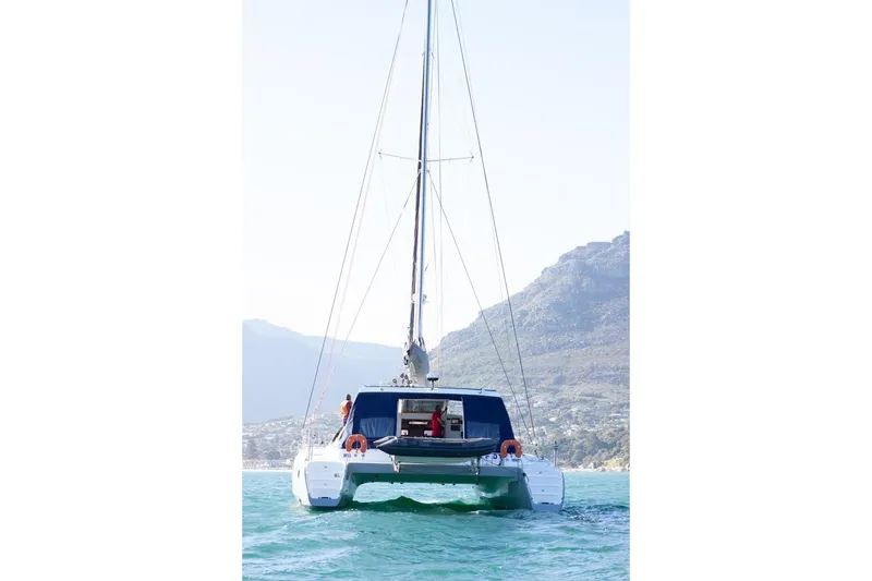 Slide: The Image of 2006 Maxim Yachts 57 catamaran sailing on clear blue water with mountainous backdrop. - 32