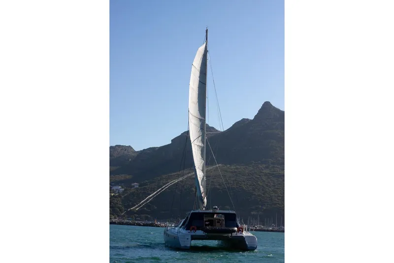 Slide: The Image of Sailing catamaran Maxim Yachts 57, 2006 model, on open water with mountainous backdrop. - 34