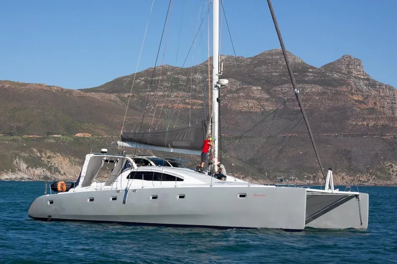 Slide: The Image of 2006 Maxim Yachts 57 catamaran sailing near rocky coastline. - 33