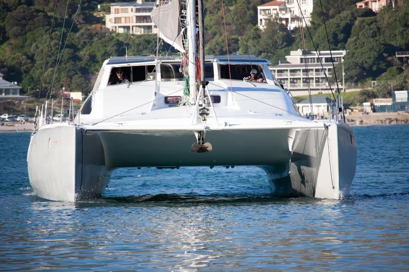 Slide: The Image of 2006 Maxim Yachts 57 catamaran sailing on calm waters near coastal homes. - 38
