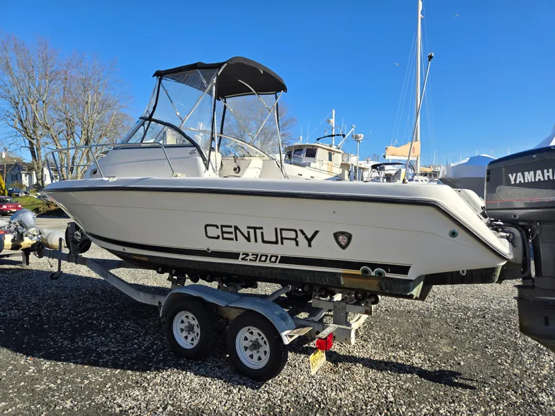 The Image of 2001 Century 2300 boat on trailer with Yamaha outboard motor, parked outdoors. - 0