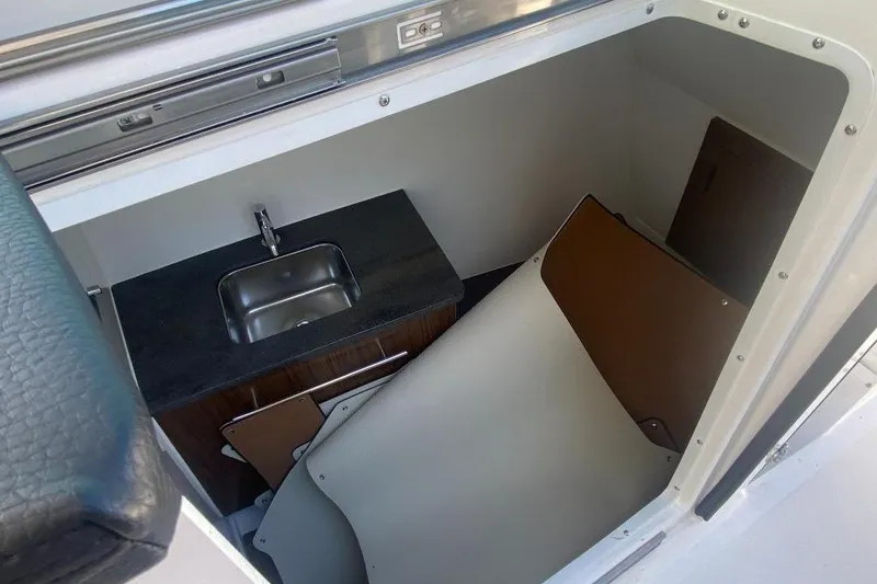 Slide: The Image of Interior of 2026 Four Winns H33 boat featuring a compact sink and storage area. - 22