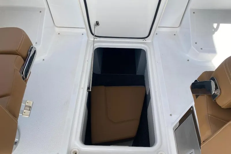 Slide: The Image of 2026 Four Winns H33 boat interior with open storage compartment and brown seating. - 24