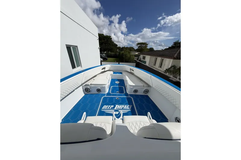 Slide: The Image of 2012 Deep Impact 399 Sport boat with blue deck and white seating under a clear sky. - 11