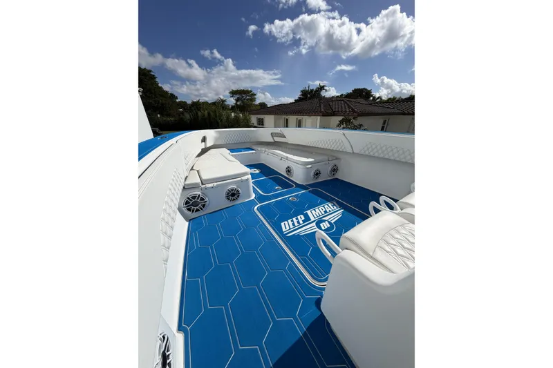 Slide: The Image of 2012 Deep Impact 399 Sport boat interior with blue flooring and white seating under a sunny sky. - 22