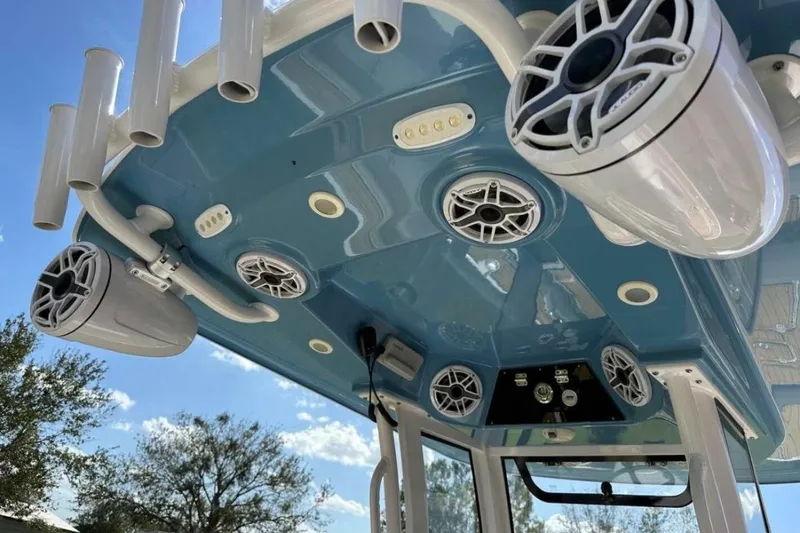 Slide: The Image of 2023 Sportsman Masters 267 Bay Boat with speakers and rod holders on blue T-top. - 6