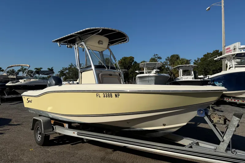 Slide: The Image of 2008 Scout 205 Sportfish boat on trailer, parked in marina under clear blue sky. - 1