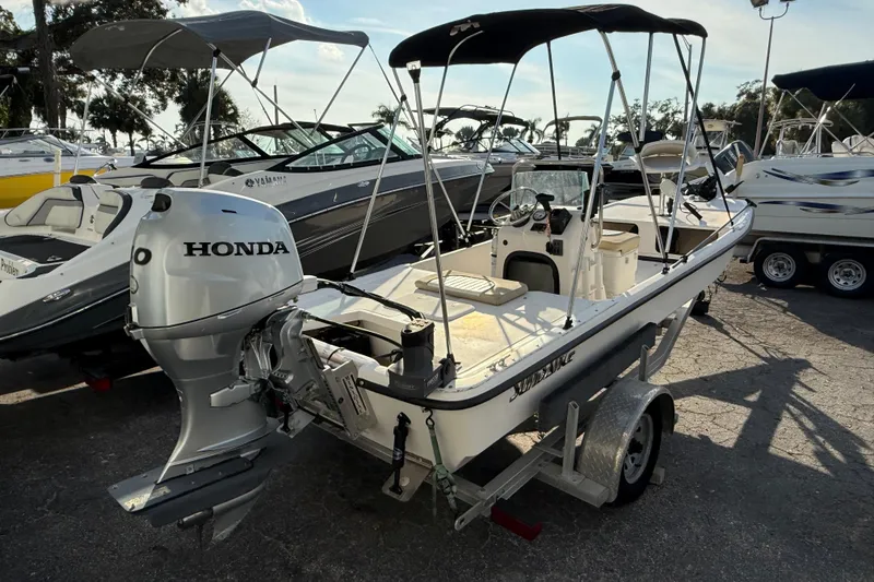 Slide: The Image of 2018 Sundance K16CC boat with Honda outboard motor on trailer in marina. - 2