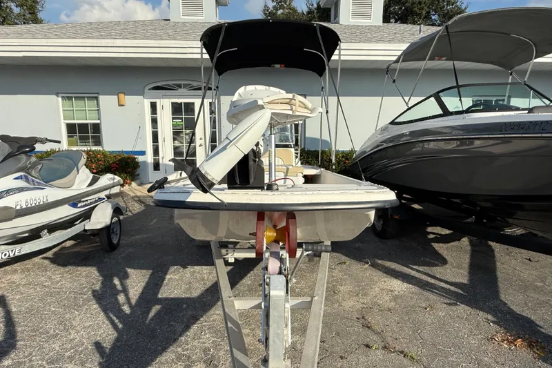 Slide: The Image of 2018 Sundance K16CC boat on trailer, parked between jet ski and speedboat. - 4